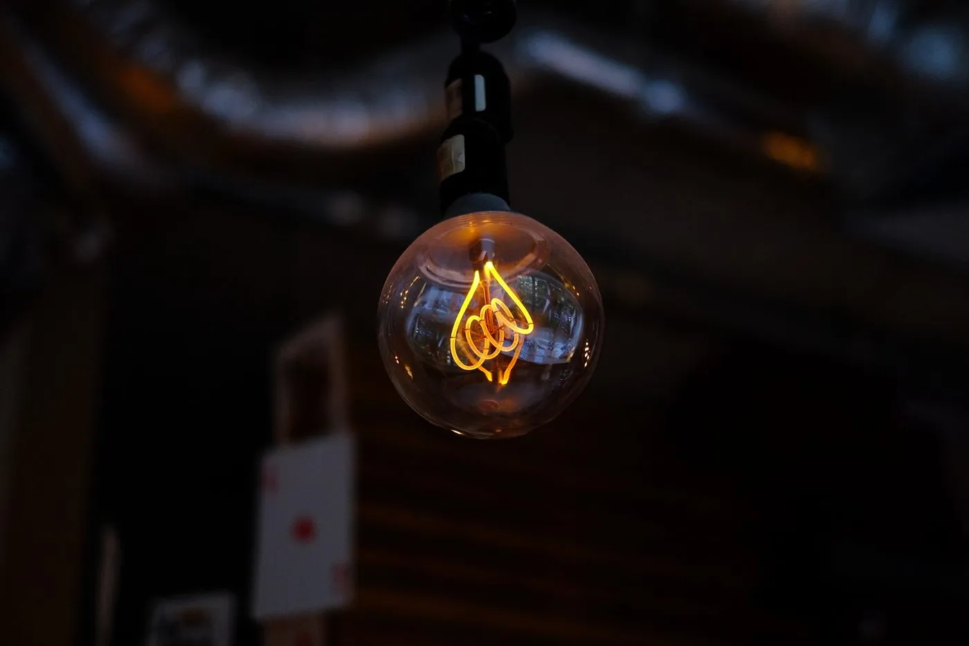 A glowing filament bulb in a dark room